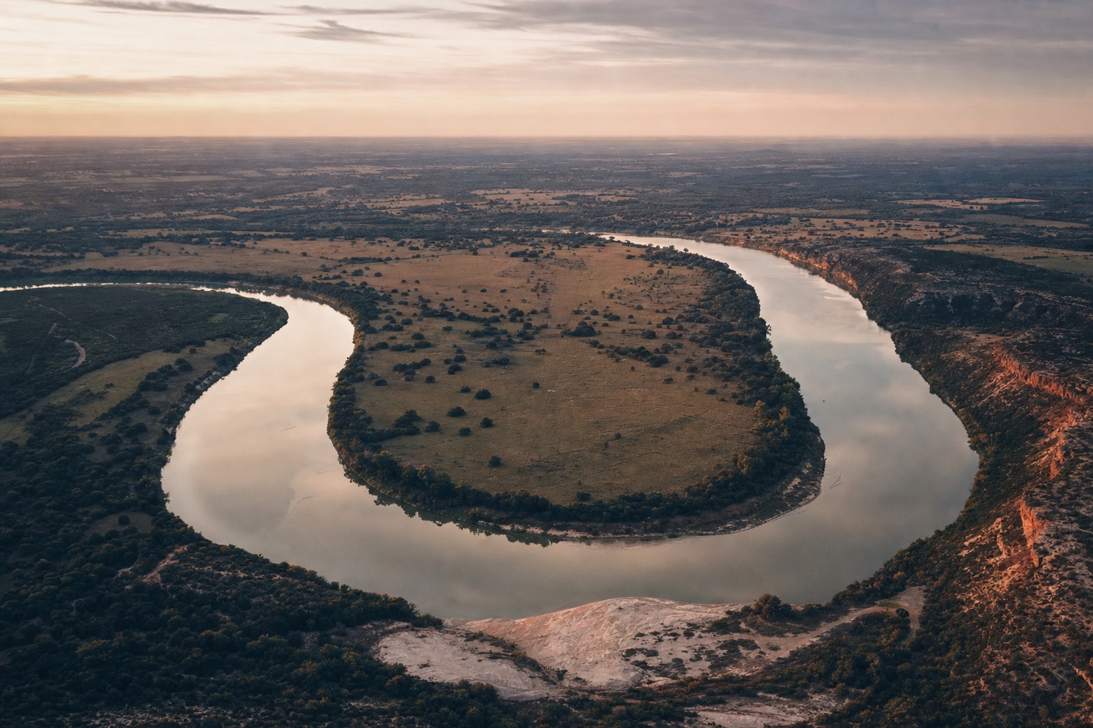 A wide bend of a Texas river at dusk, seen from the air